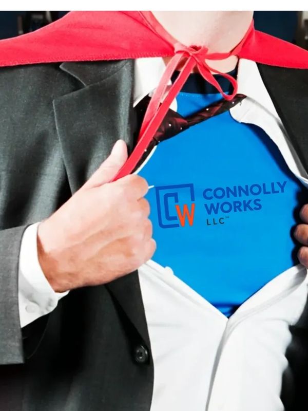 Man in a suit and red cape revealing a Connolly Works LLC logo shirt to an applauding audience.