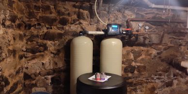 Water softener system installed in a stone basement.