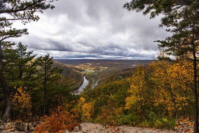 Scenic autumn valley with river and hills under a cloudy sky.