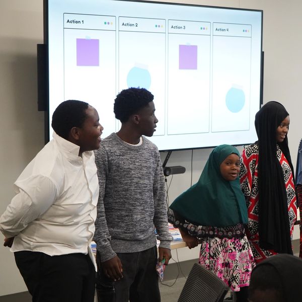 Group of young people standing in front of a presentation screen.
