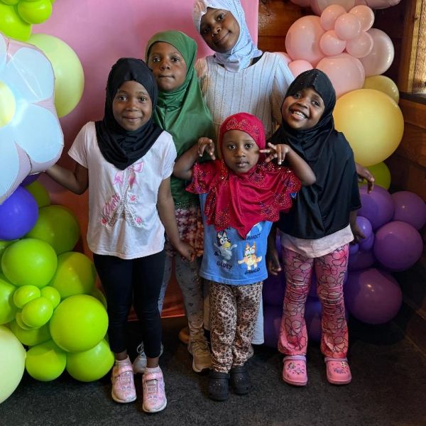 Five children posing with colorful balloons.