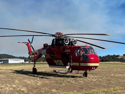 Red firefighting helicopter on grassy field.