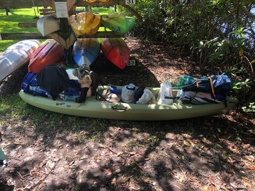 Loaded kayak with camping gear on grass.