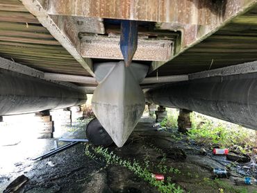 Bottom view of a boat under a wooden dock.