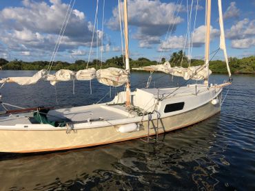 Sailboat anchored on calm water under a partly cloudy sky.