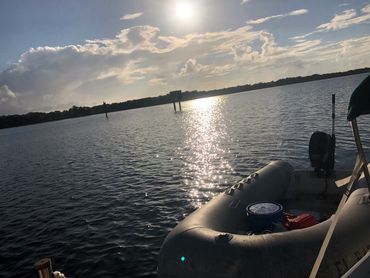 A boat floating on a calm water body under a partly cloudy sky.