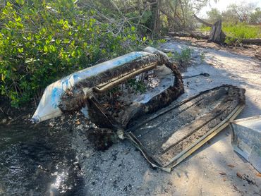 Partially submerged, damaged inflatable boat on shoreline.