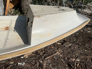 Old small boat hull lying on the ground.