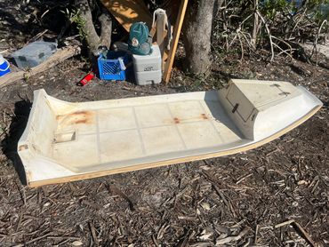 Small white flat-bottom boat on land.