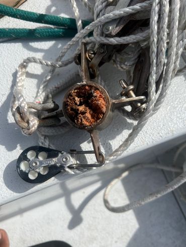 Close-up of corroded marine pulley and ropes.