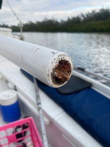 Close-up of a damaged white pipe on a boat by water.