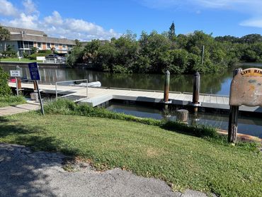 A small dock on a calm waterfront with greenery.