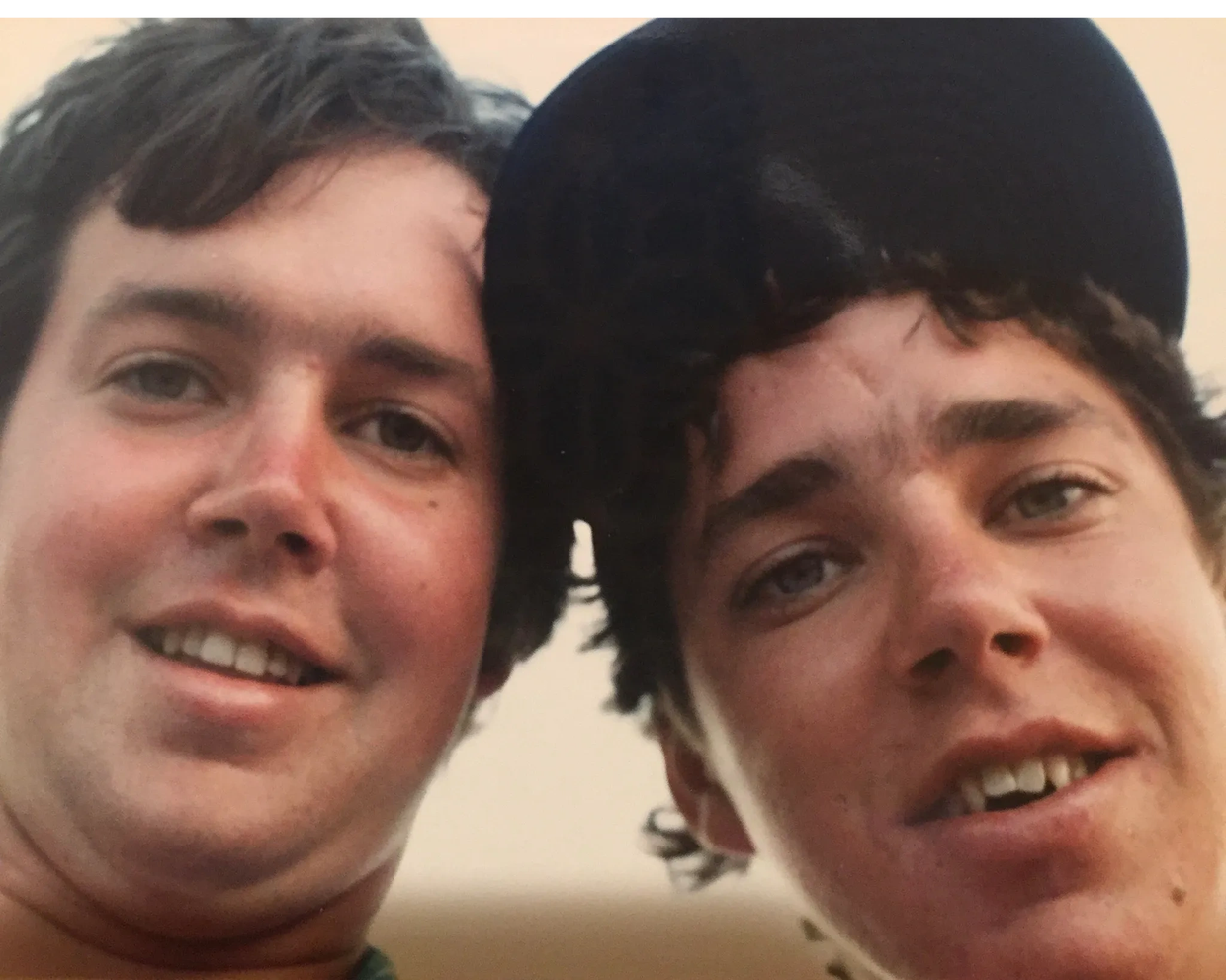 Two young men smiling close to the camera.