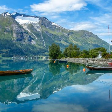 Boats on a clear lake with mountain reflections.