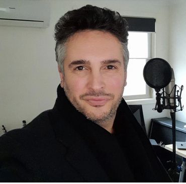 Man taking selfie in a music studio with microphone and guitar.