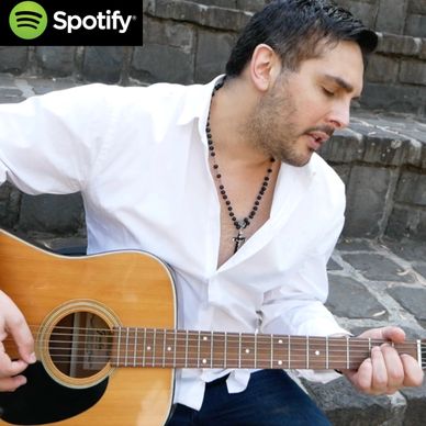 Man in white shirt playing acoustic guitar outdoors on stone steps.