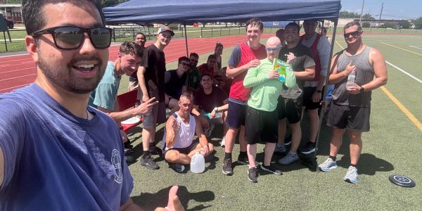 Group of athletes posing happily on a sports field.