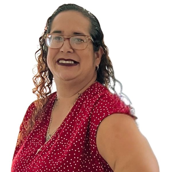 Smiling woman wearing glasses and a red polka dot dress, posing with hand on hip.