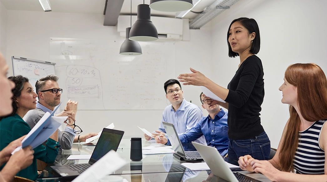 Woman speaking to group around office table