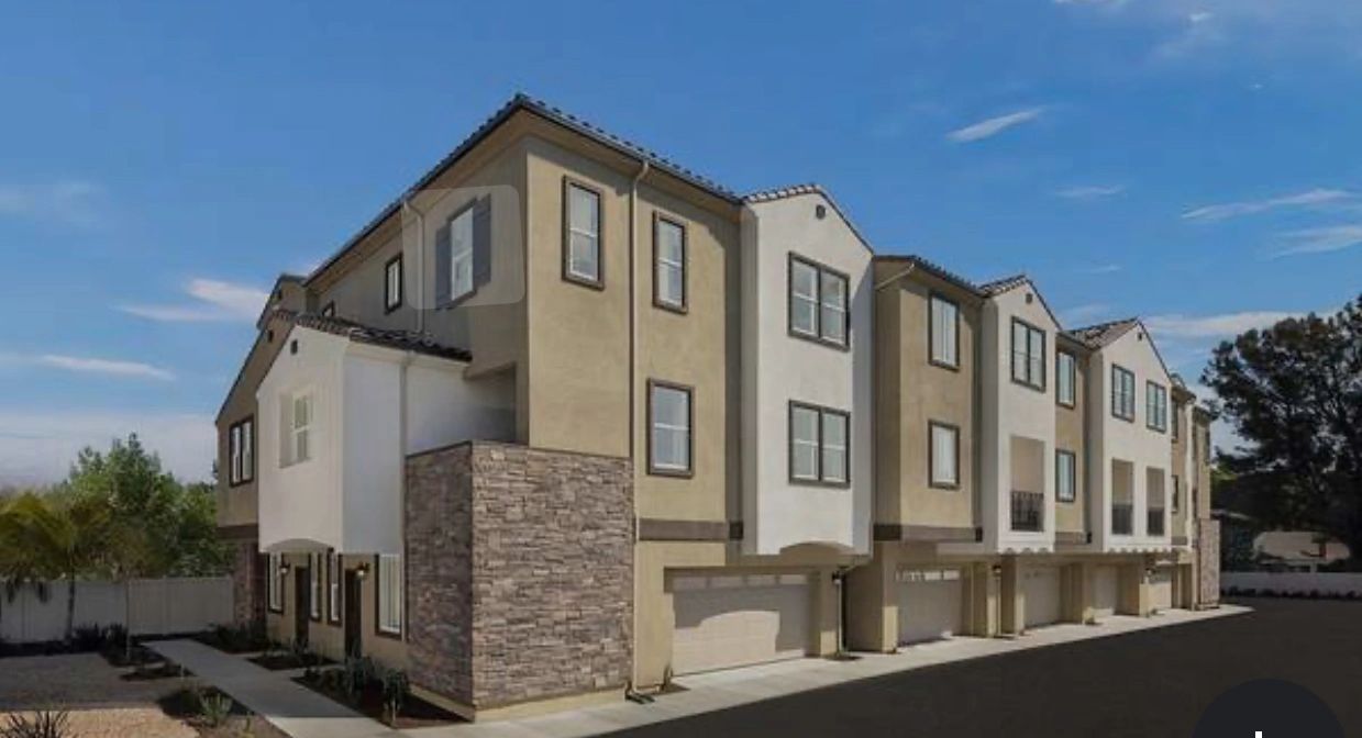 Modern townhouse complex with garages under bright blue sky.
