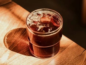 A glass of iced coffee on a wooden surface.