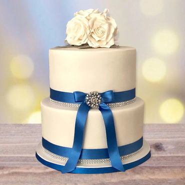 Simple 2 tier wedding cake covered with fondant with blue ribbons and diamanté brooch