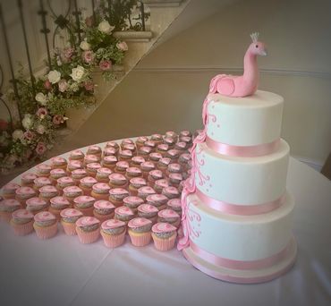 Pink peacock wedding cake with cupcakes