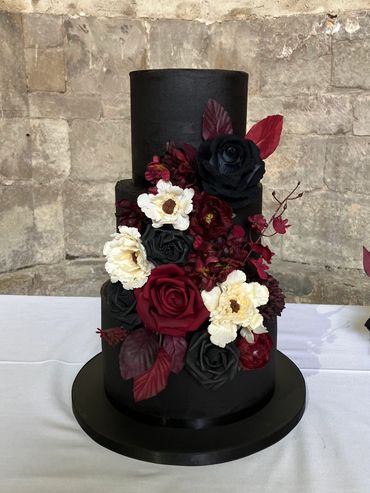 Black buttercream wedding cake with  black, red and cream flowers
