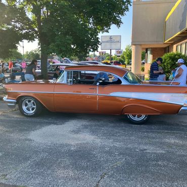 Vintage orange and silver car parked outdoors.