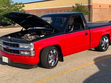 Red pickup truck with hood open in parking lot.