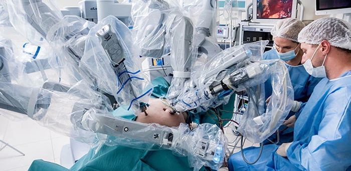 Surgeons operating with robotic assistance in a high-tech surgical room.