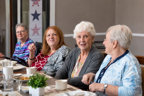 Four elderly women enjoying a meal and conversation together.
