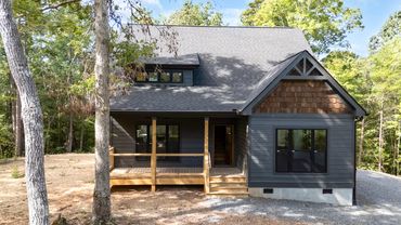 An iron ore custom modern cottage with big square windows and covered porches on a crawl space