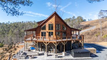 A custom log cabin home built on a slab foundation with wrap around deck and patio and a prow front