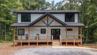 A black & white custom home with big covered porches and large windows built on a full basement