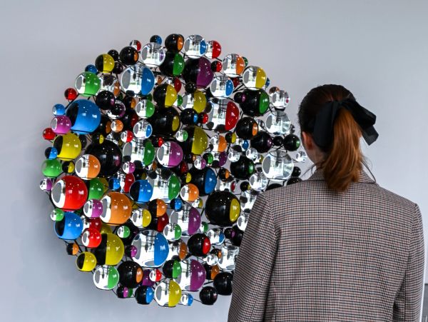 Woman viewing colorful circular mirrored wall art.