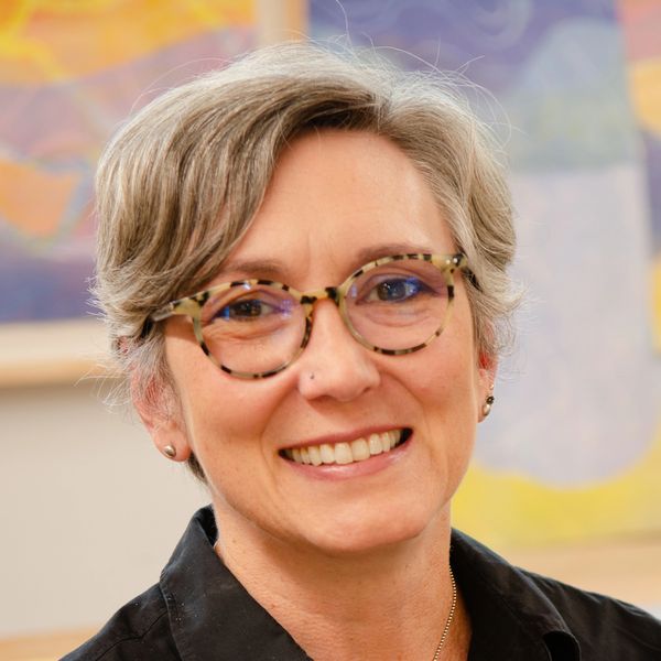 Smiling woman wearing glasses, short gray hair.
