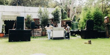 People setting up audio equipment outdoors on a grassy lawn.