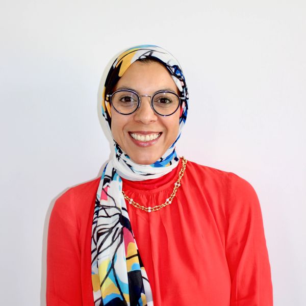 Smiling woman wearing glasses and colorful hijab.