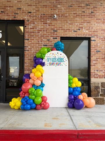 Colorful balloon arch around a sign celebrating Ivy Kids Hobbs' seven-year milestone.