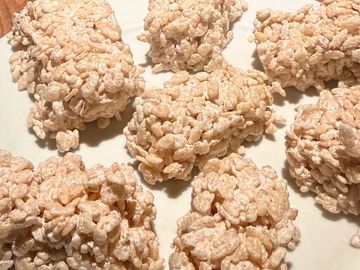 Close-up of homemade rice crispy treats on a white surface.