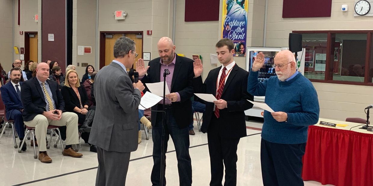 Three men being sworn in during a formal ceremony.