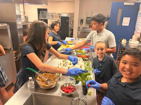 Kids preparing food in a kitchen wearing gloves.