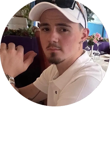 Young man in white cap and shirt sitting indoors.
