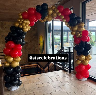 Balloon arch decoration in black, red, and gold.