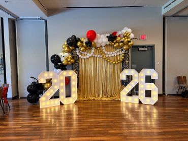 2026 graduation photo booth with illuminated numbers and balloon decor.