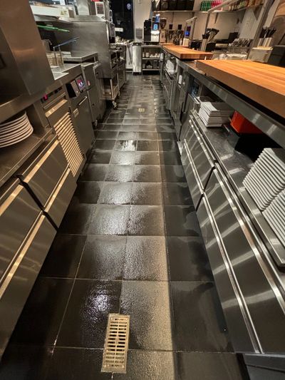 Clean commercial kitchen with shiny tiled floors and stainless steel appliances.