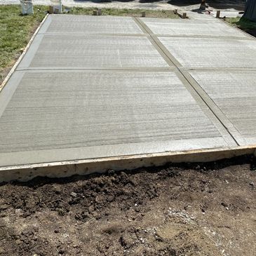 Freshly poured concrete slab with visible sections and smooth finish.