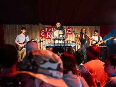 Band performing on stage with audience watching.