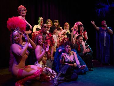Group of performers posing on stage in colorful costumes.